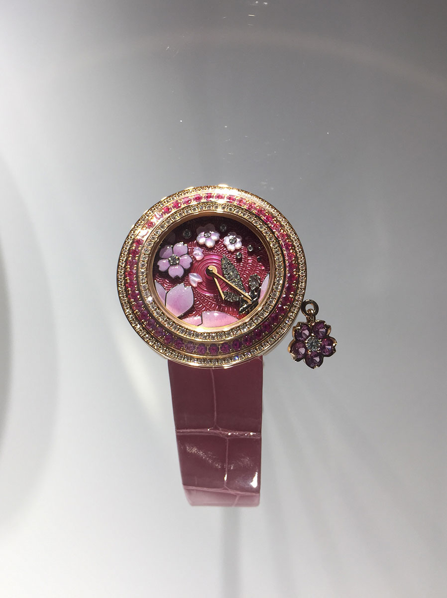 以盛放的樱花为灵感的 Charms Extraordinaire Fée Sakura 腕表，继在东京银座旗舰店开幕时首度亮相之后，此次于2017日内瓦国际高级钟表展(SIHH) 璀璨登场。在深粉红色的表盘之上，世家以多项精湛的传统工艺刻画出引人入胜的自然景致︰手工雕刻和上色的珍珠母贝，勾勒出樱花的细腻美态，表盘上前排的花朵则通过凸圆型珐琅工艺完美呈现，乳白色的花瓣隐约透现出立体层次。