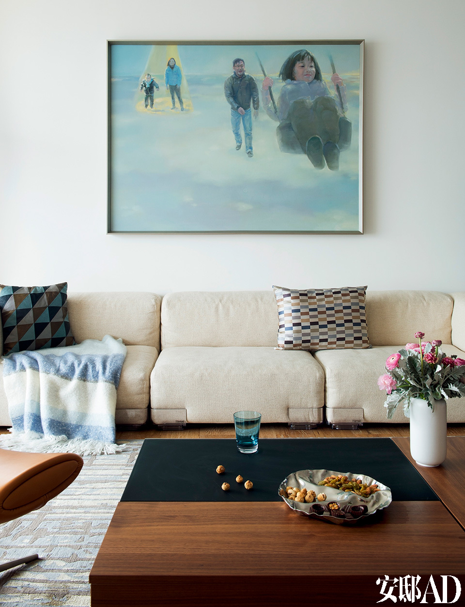 正是根据这张油画全家福，设计师为新家定下了整体色调。沙发上的几何图案靠垫来自BoConcept北欧风情，毯子购自ZARA HOME，不锈钢托盘由Alessi出品。
