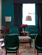 客厅中，近处Grant Featherston的1960 Scape椅与对面孔雀蓝的Sensuede路易十五风格扶手椅相映成趣，一旁是Artemide Tolomeo的阅读灯，像素化的亮色地毯在Living Art Gallery定制。
