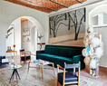 老建筑有新房子无法比拟的魅力，不规整的线条反而给它带来有机的生命力！绿色天鹅绒沙发“P17 Sant’Ambrogio”和独立扶手椅样品“P21 Chinotto”，它们都是由
建筑师Luigi Caccia Dominioni设计、由意大利Azucena生产的。沙发前面是意大利设计师Paolo
Buffa设计的20世纪40年代长方形茶几。黑色桌脚的圆形茶几是意大利设计师Pietro Chiesa
（1892-1948）为Fontana Arte设计的家具之一。