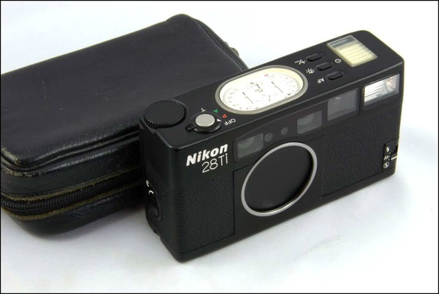 NO.2 Nikon 28Ti
尼康这台28Ti和35Ti都带一个Ti，一方面代表了机身采用了“钛”材料，另一方面说明价格不会低。该相机采用的是28mm F2.8镜头。相机的外观设计和28Ti类似，十分具有触感。采用“钛”金属的最大优点就是，按快门的声音十分清脆好听，几乎没有机震的感觉。该相机机身上也有椭圆形指针显示屏，显示各参数信息。
