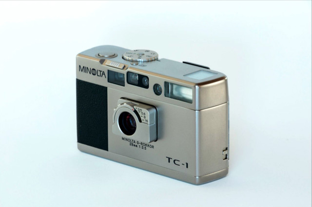 NO.3 Minolta TC-1
这款美能达的TC-1，外观小巧精致，设计也不落俗套。作为袖珍相机，它出色的操控性、G-ROKKOR 28mm f/3.5高画质的镜头不无透露出身份的高贵。机身同样为钛金属，手感极佳，再配上复古的皮套，与其说是一件相机不如说是一件值得珍藏的收藏品。

