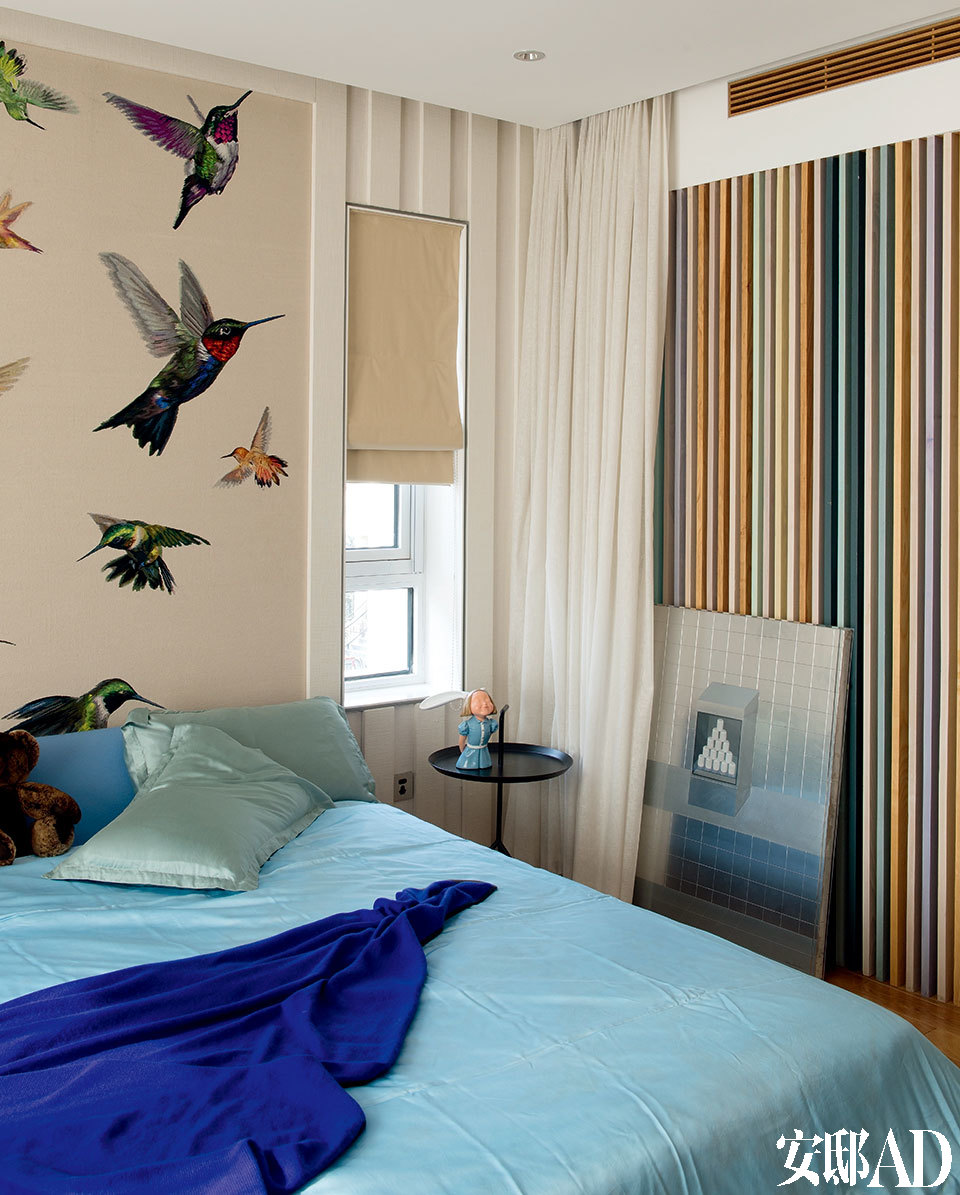 主人女儿的卧室中，连木格栅都调成了彩色，床头墙面挂的实际是一块地毯，地上的画作来自Huang Yi Shan。