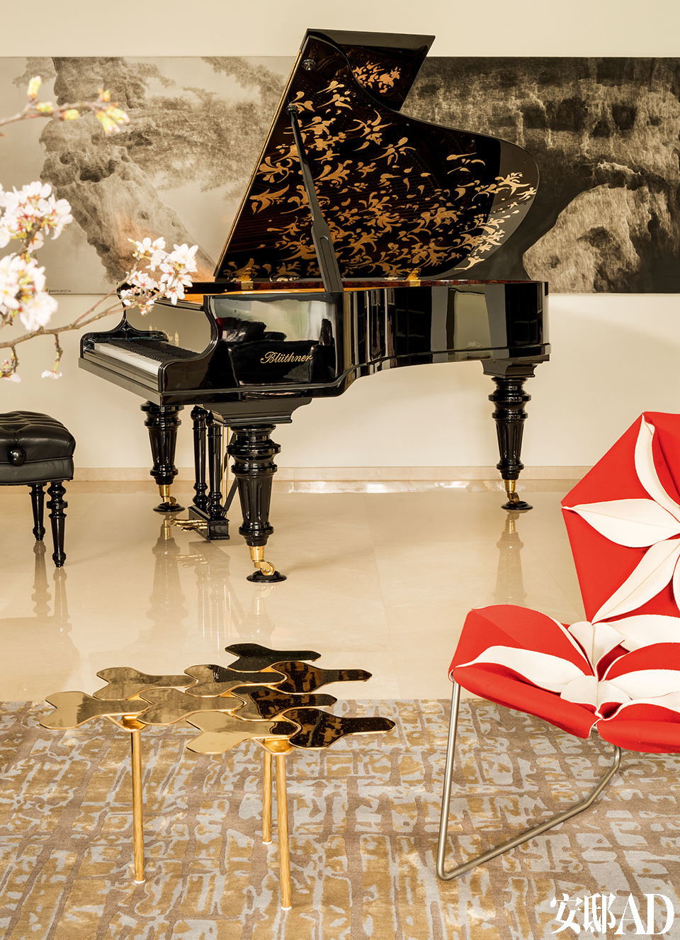 钢琴上的金色漆画呼应着现代造型的小茶几，音乐与设计在这个家中相互交融。客厅的另一侧摆着
Blüthner的Julius大师版钢琴，钢琴后面的画作由雪松创作。
