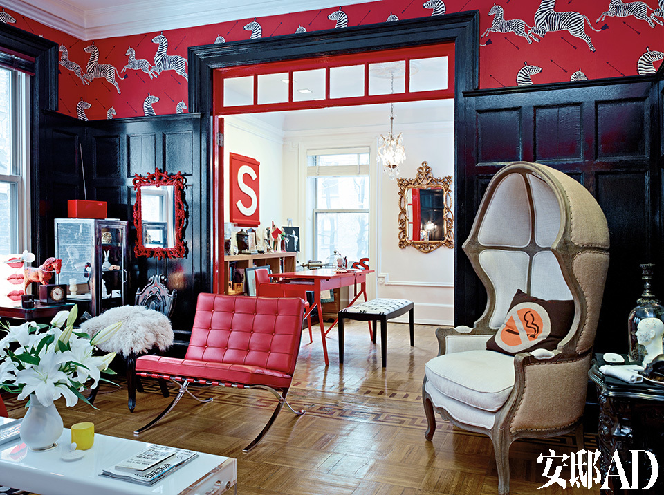 客厅以及主人的餐厅兼书房中，黑红主色调以及各种风格的混搭效果非常惊艳。天然白的经典连帽座椅购于纽约Restoration Hardware，一旁是红色的“巴塞罗那”椅，靠墙的金色巴洛克式镜子购自Horchow。