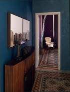 从客厅向卧室望去，质朴的地砖起到了非常关键的衔接作用，它也为墙面的用色提供了灵感。客厅木制抽屉柜上方的艺术品是由 Lorenzo Butti创作的，而柜子上摆放的台灯是Ugo Ambroggio的作品。